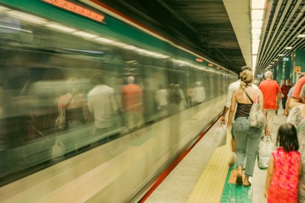 Commuters wait as a subway train passes by, capturing the hustle of urban travel.